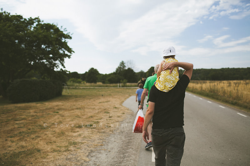 Familj går på en väg mot Gyllebosjön. Foto: Tove Lundquist, fotograf Österlen. (reportagestil)