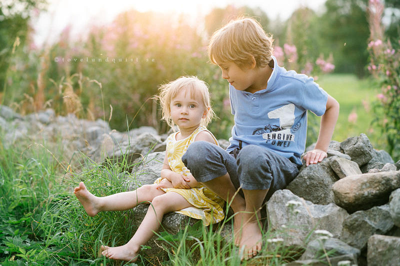 Syskon sitter på en stengärdsgård i Sillaröd. Familjefotograf Österlen Tove Lundquist erbjuder lifestyle fotograferingar tillsammans med er familj.