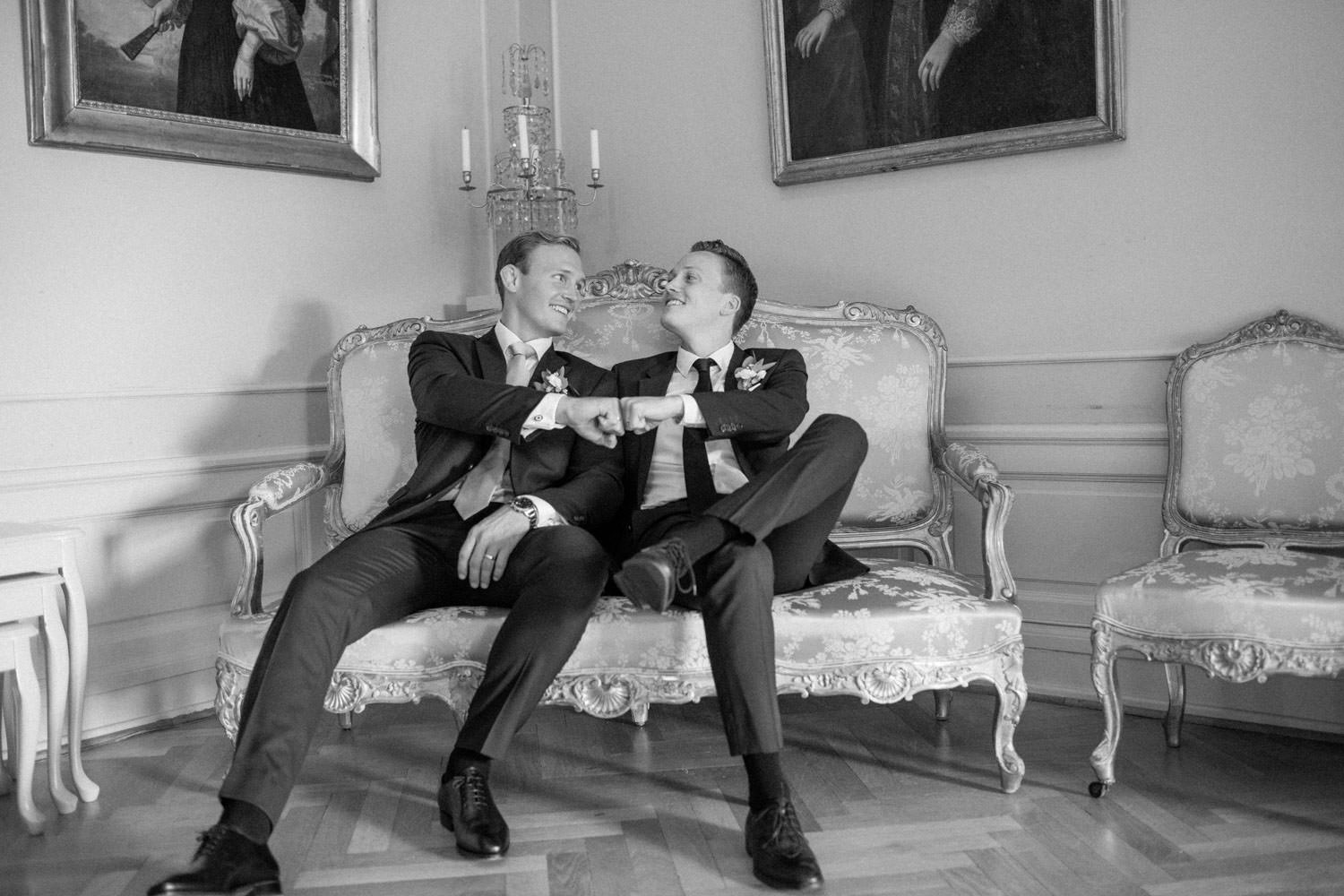 Två bröder sitter i en soffa inomhus under ett bröllop på Trolleholms slott i Skåne.