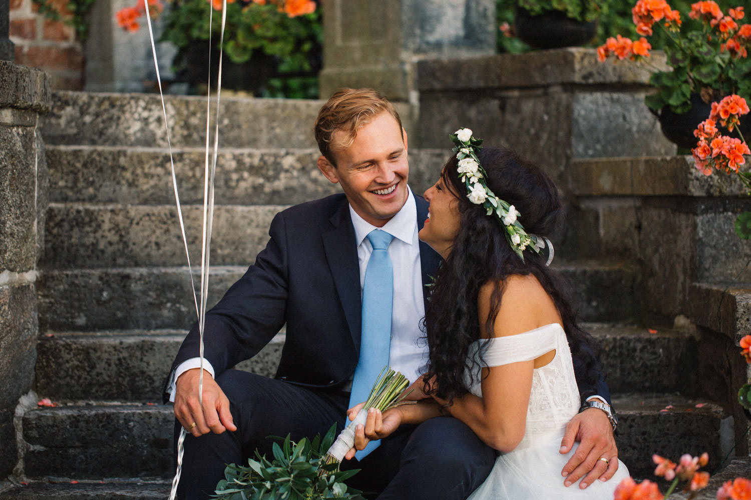 Brudparet Christoffer och Ashley Ljungbäck sitter på trappan vid Trolleholms Slott. Foto av Tove Lundquist, bröllopsfotograf Skåne.