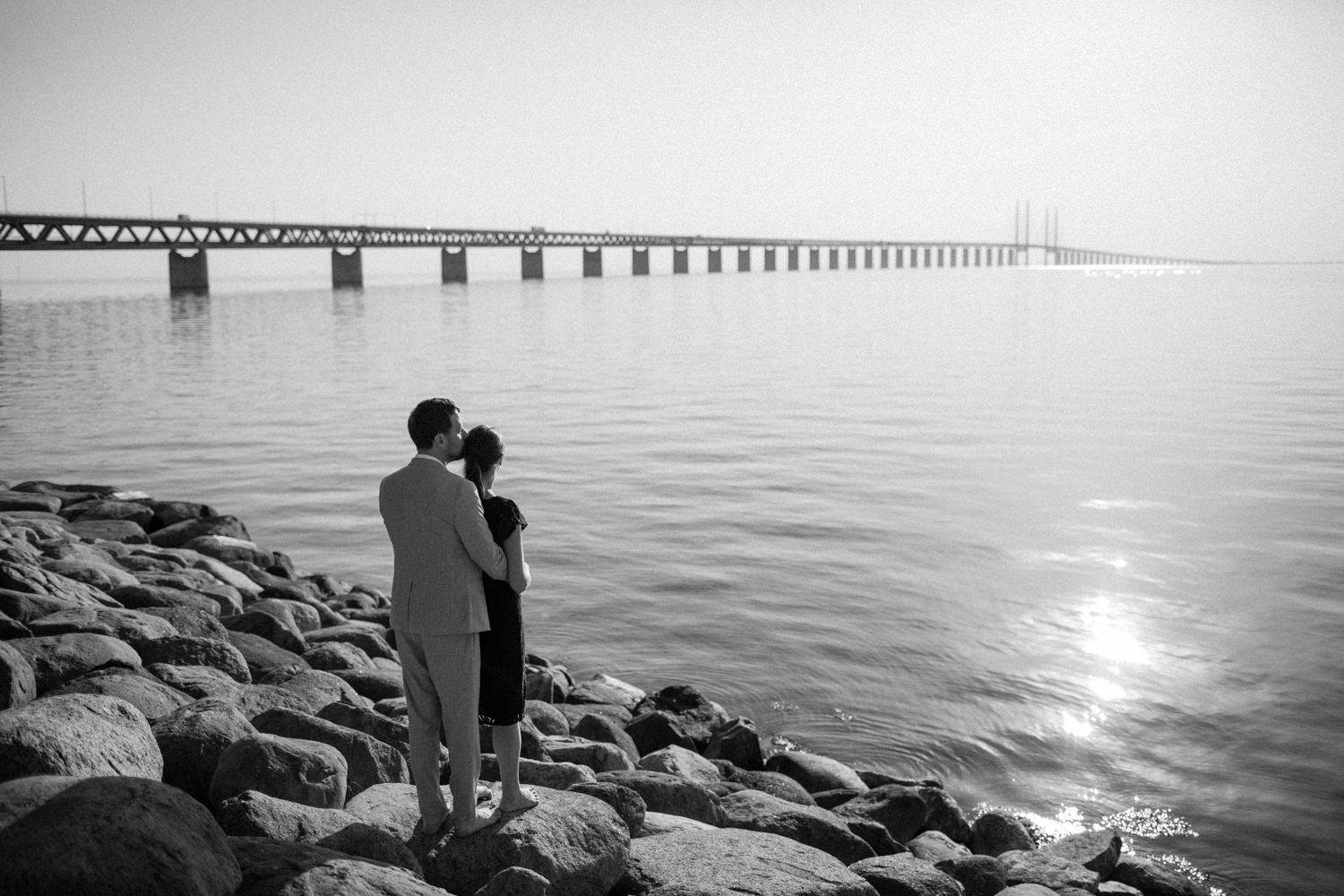 Svartvitt foto på brudpar som tittar ut över havet vid Utsiktspunkt Öresundsbron. Fotografen är Tove Lundquist, Skåne.