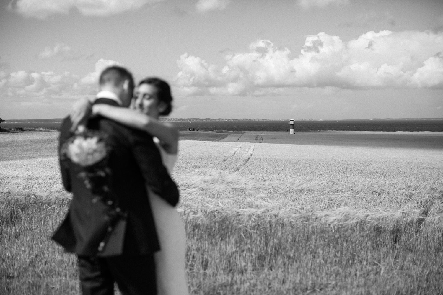 Internationellt svenskt-amerikanskt bröllop på Ven, porträtt på brudparet vid havet och åker. Foto: Tove Lundquist.