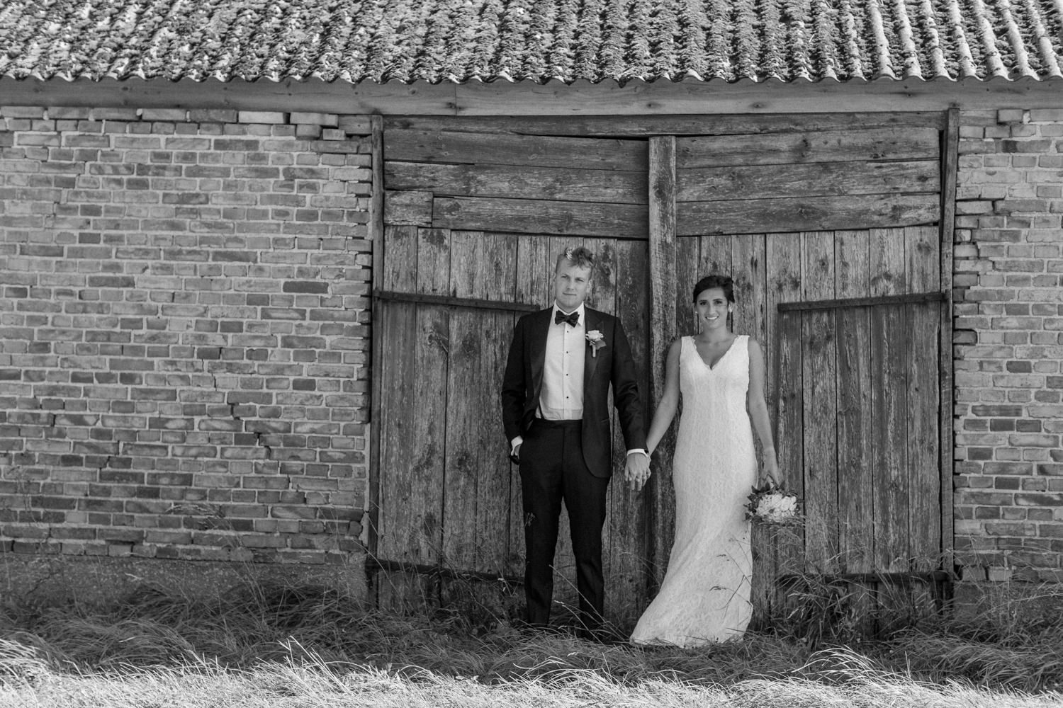 Internationellt svenskt-amerikanskt bröllop på Ven, porträtt på brudpar vid lada. Foto: Tove Lundquist.