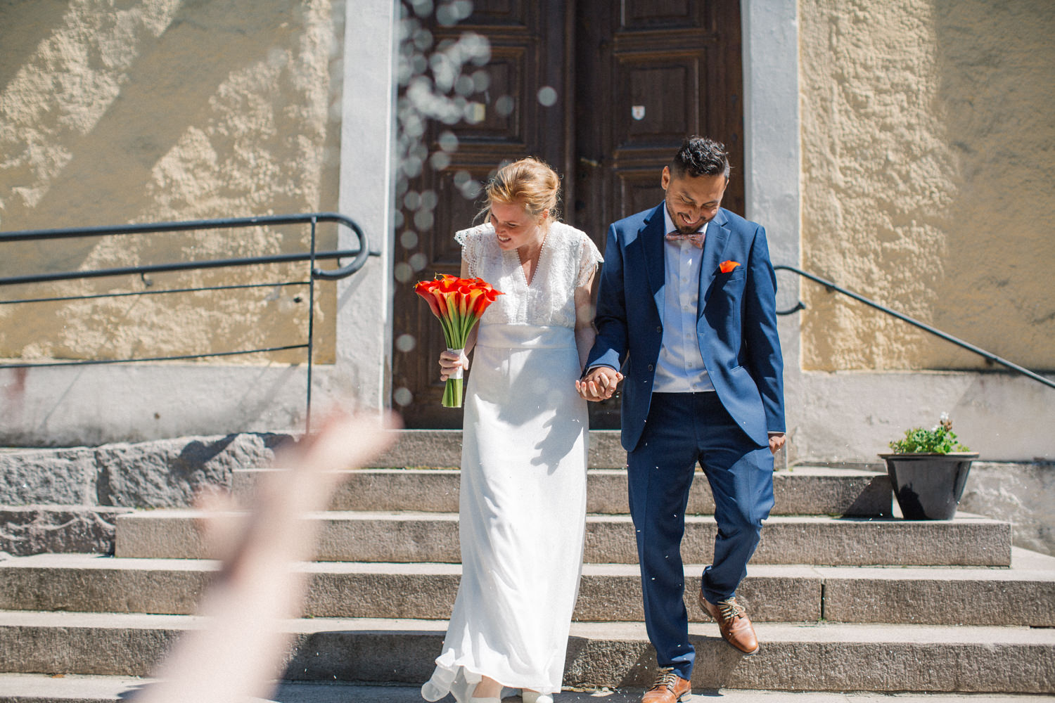 Vigsel i Sankta Maria kyrka, Borrby, brudparet kommer ut på trappan och ris kastas. Fotograf: Tove Lundquist.