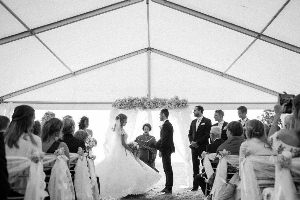 Utomhusvigsel vid regn - ett vitt tält som bröllopslokalen erbjuder vid regnigt väder. Foto: Tove Lundquist, bröllopsfotograf i Skåne.