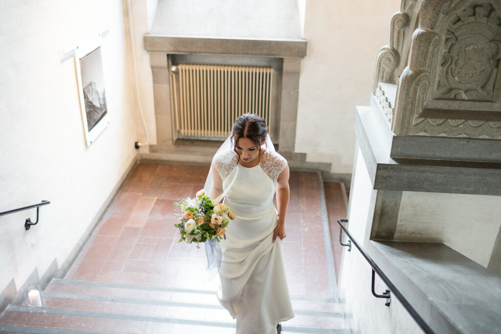 En brud kommer gående i trappan på High Court under en inomhusvigsel. Foto: Fotograf Tove Lundquist. Brudklänningen kommer från Skräddarhuset i Malmö, bröllopsbuketten från Gouteva.