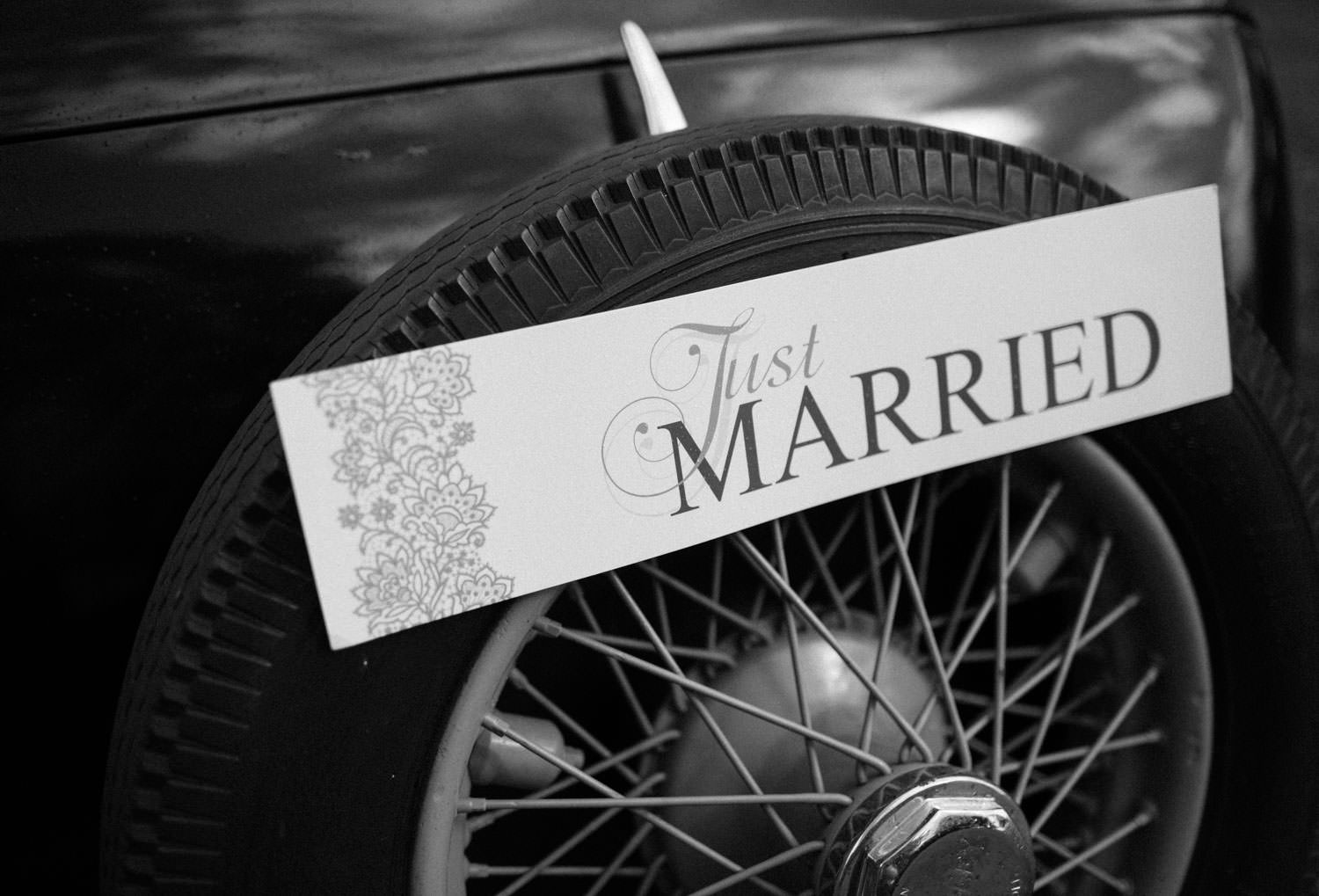 Svartvitt foto på en Just Married skylt som sitter på en bil.