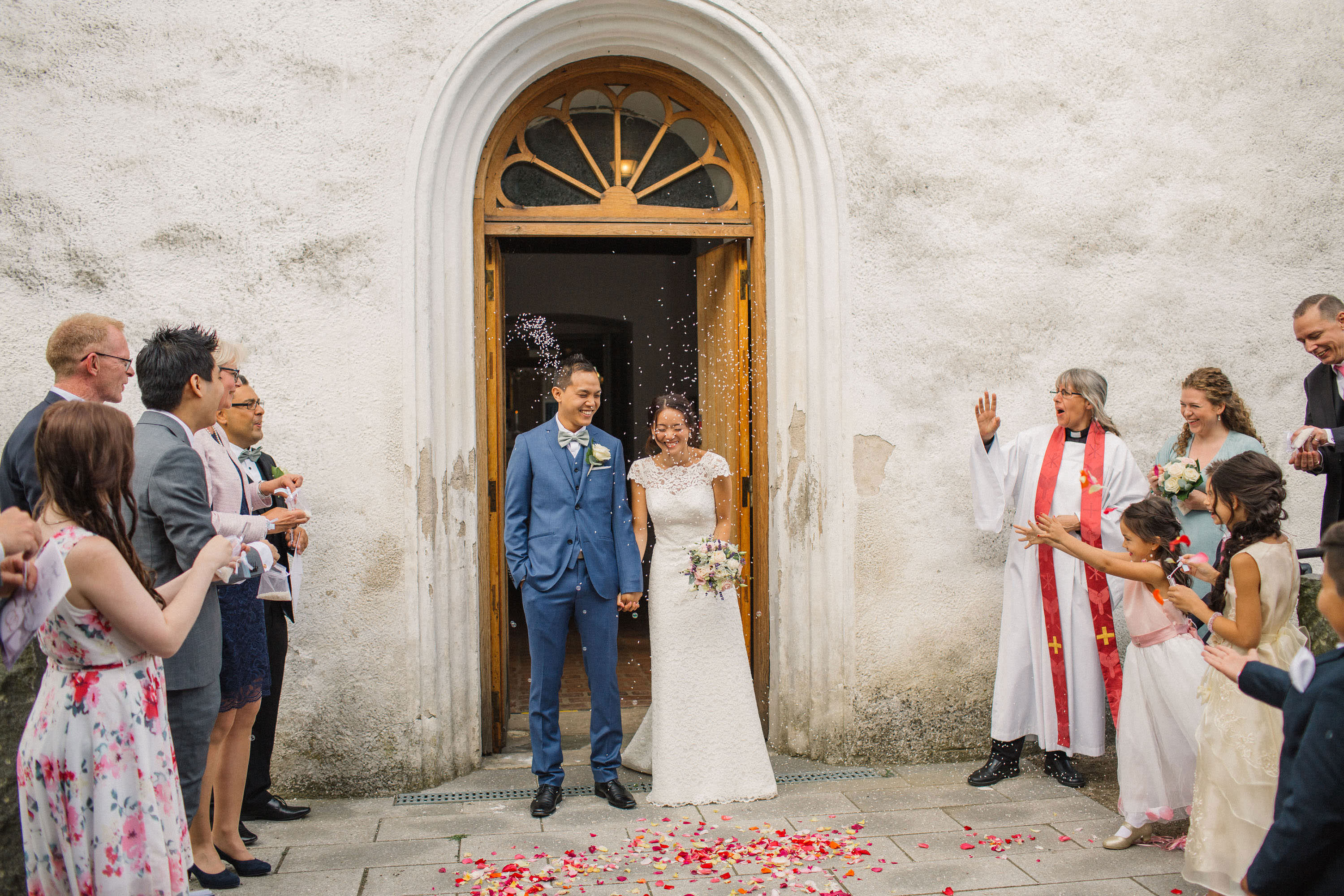 Brudpar efter en kyrklig vigsel i Borgeby kyrka, Bjärred. Ris och rosblad kastas på brudparet. Foto av Tove Lundquist, bröllopsfotograf i Skåne.