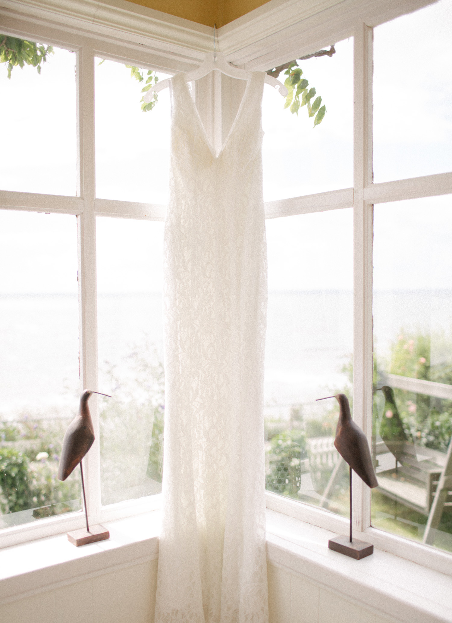 Bild i färg på brudklänning upphängd i fönster under ett bröllop på Ven. Bröllopsfotograf är Tove Lundquist.
