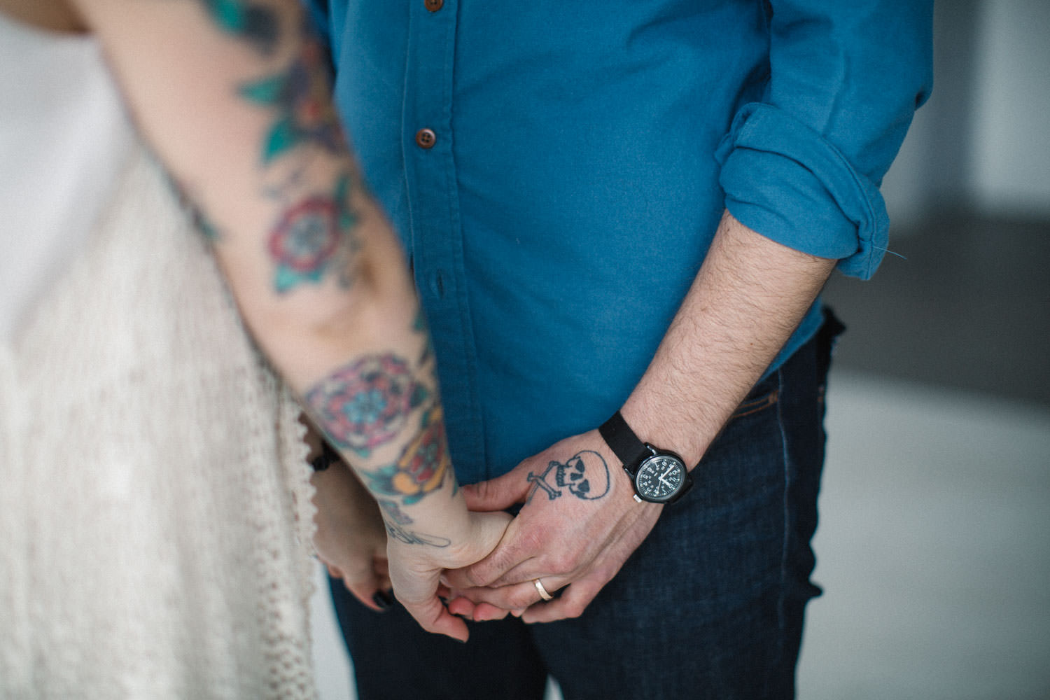 Bild i färg på ett tatuerat par som håller varandras händer. Foto: Tove Lundquist, porträttfotograf Malmö.