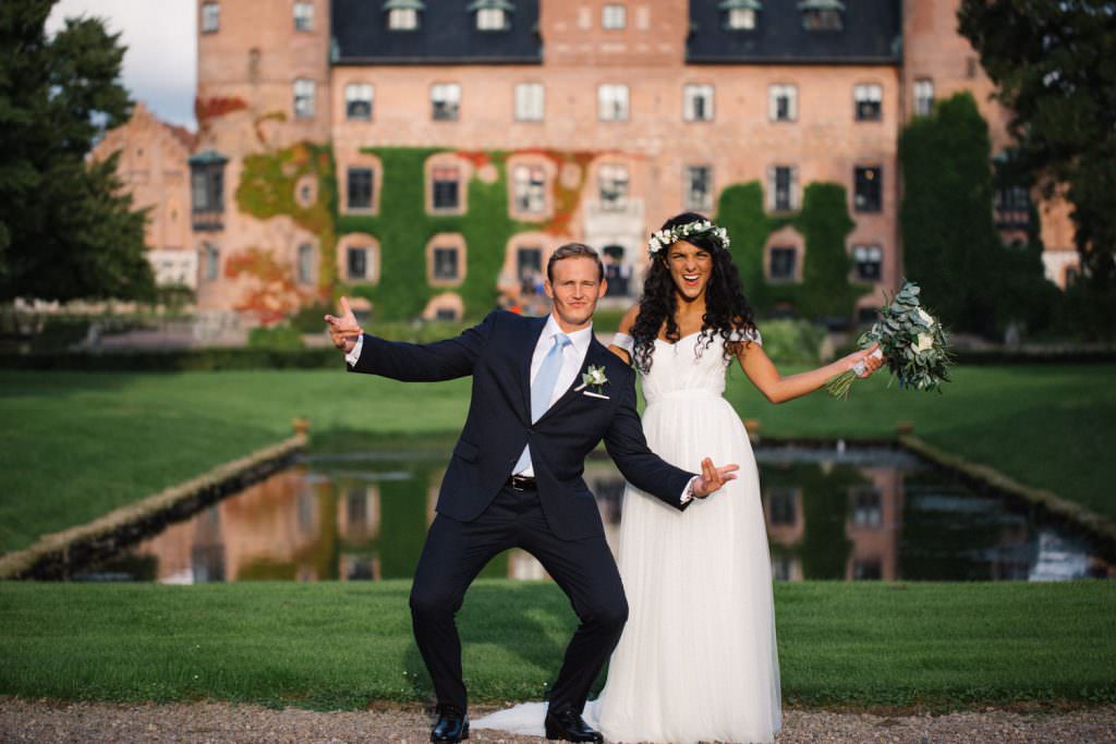 Ett glatt brudpar firar sitt bröllop utanför Trolleholms Slott. Foto av Tove Lundquist, bröllopsfotograf Skåne.